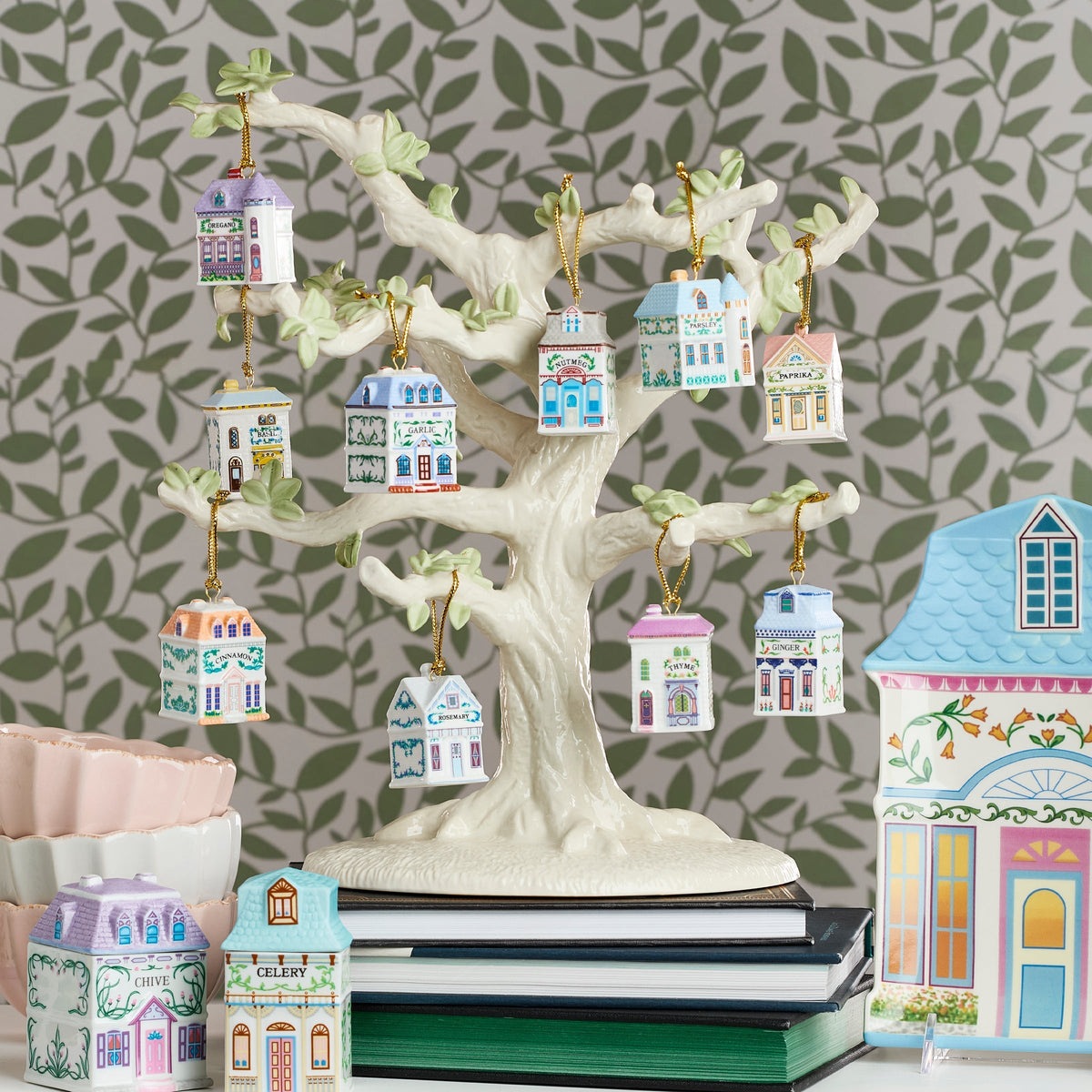 Decorative tree with small house ornaments against a leaf-patterned wall.